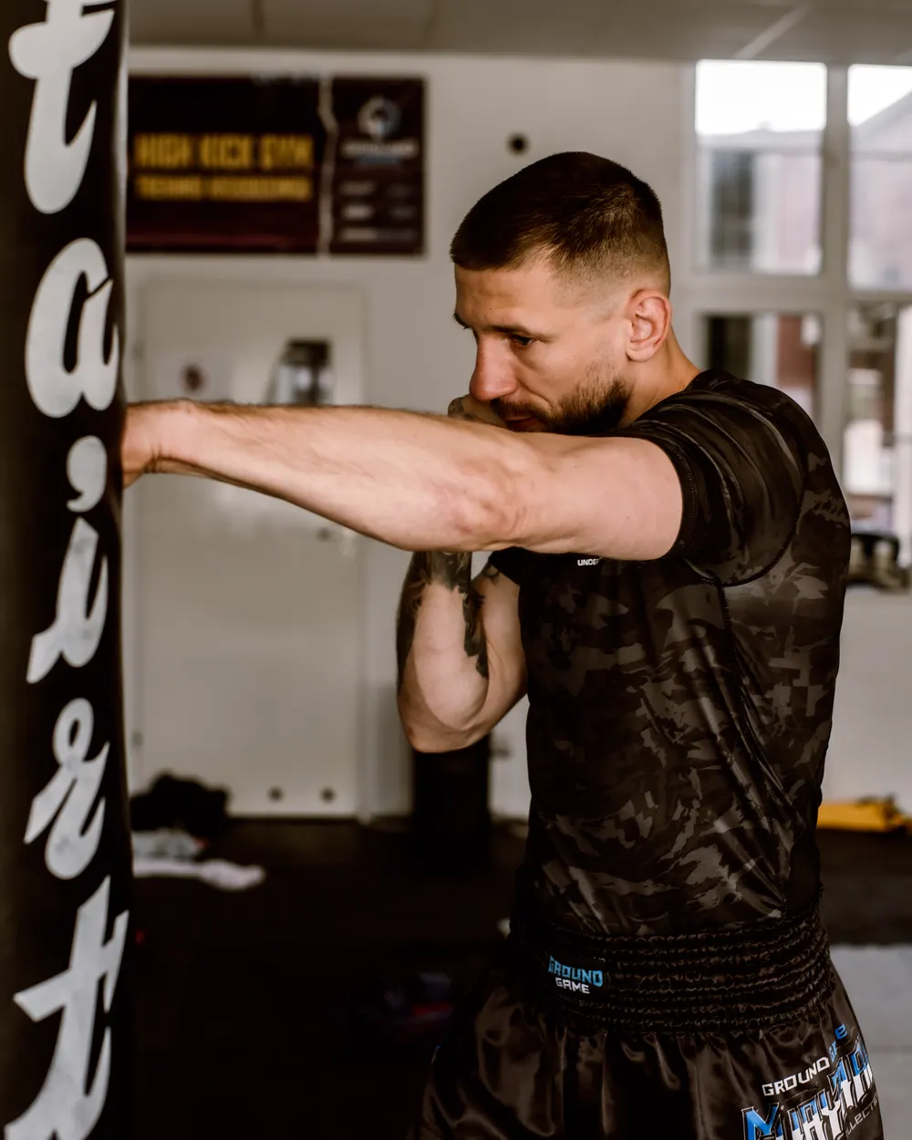 Marcin Kujawa wyprowadza prosty cios w worek treningowy w klubie High Kick Gym