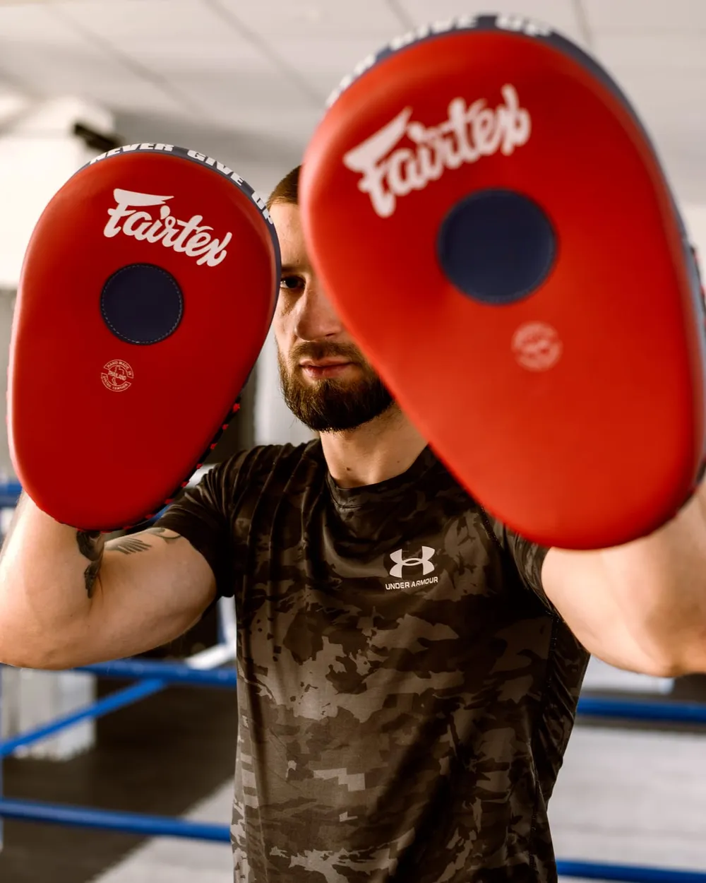 Trener trzyma dwie tarcze Fairtex, gotowy do sesji sparingowej
