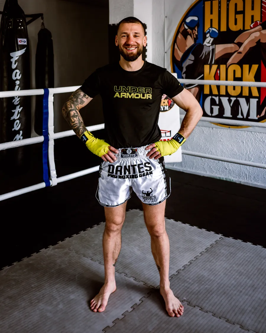 Marcin Kujawa, uśmiechnięty trener personalny i dietetyk, w klubie High Kick Gym w Szczecinie